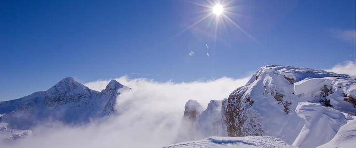 Sol sobre las cumbres nevadas entre nubes bajas