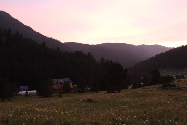 Valle y siluetas de montaña bajo un cielo de atardecer