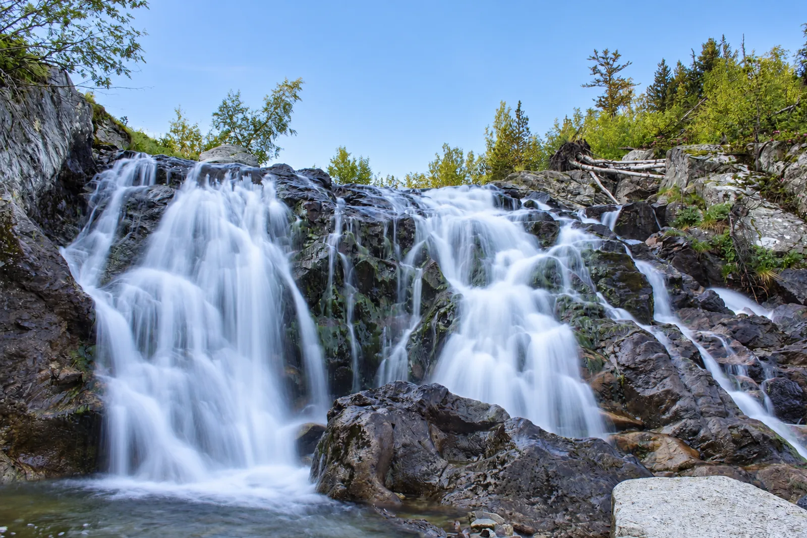 Cascada de Aiguamòg entre rocas bajo un cielo claro de mañana